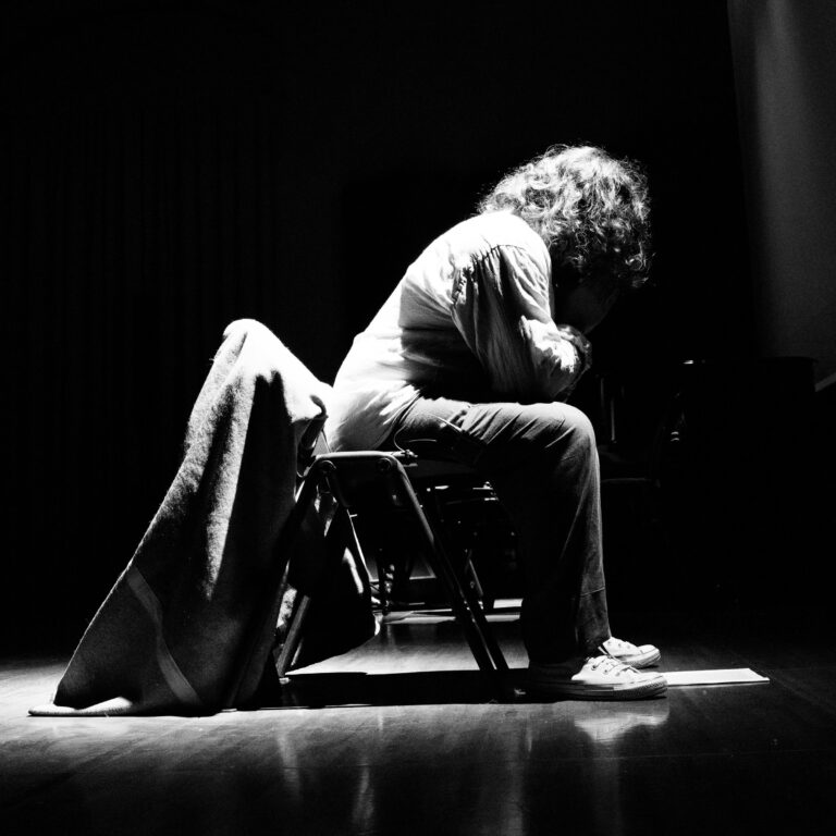 Giulio Cavalli seduto sul palco in A casa loro