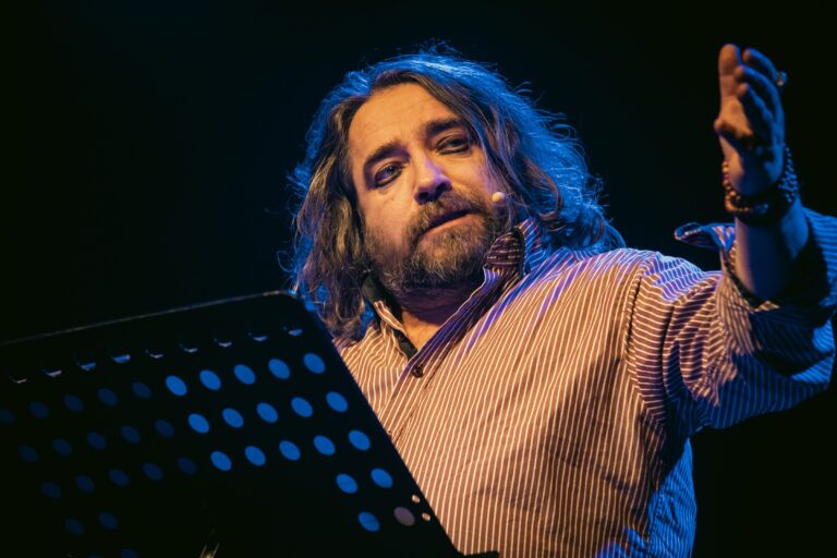 Giulio Cavalli in scena con il leggio, luce blu